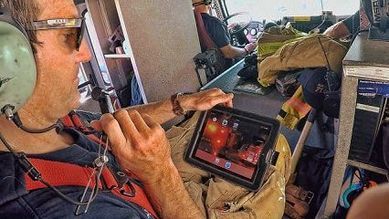 Responder in a headset reviewing LR-x on a tablet inside a vehicle